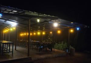 a covered patio with tables and chairs at night at Campper Campwoody Munnar in Munnar