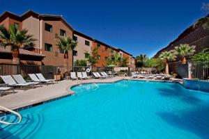 a large swimming pool with lounge chairs and a hotel at TownePlace Suites St. George in St. George