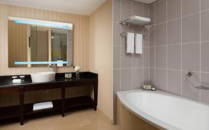 a bathroom with a tub and a sink and a mirror at Renaissance by Sulo in Aktau