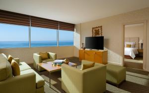 a living room with a couch and chairs and a television at Renaissance by Sulo in Aktau