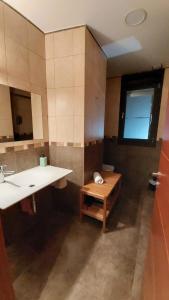 baño con lavabo, espejo y banco en Alojamientos Marel Sanabria, en Villarino de Sanabria