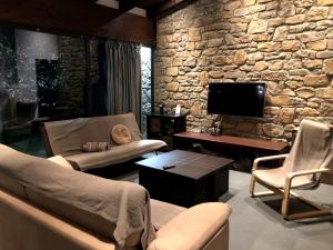 ein Wohnzimmer mit 2 Sofas und einer Steinmauer in der Unterkunft Alojamientos Marel Sanabria in Villarino de Sanabria
