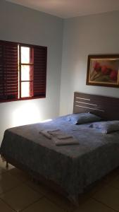 a bedroom with a large bed with two windows at Hotel Calema in Capitão Leônidas Marques