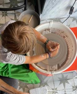 a woman is working on a pottery wheel at 19 Tile Ceramic Concept - by Unlock Hotels in Caldas da Rainha