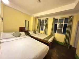 a hotel room with two beds and two windows at HOTEL PURNI DARJEELING in Darjeeling