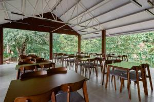 uma sala de jantar com mesas, cadeiras e árvores em Baan Rai Santisuk em Ban Sok Dua