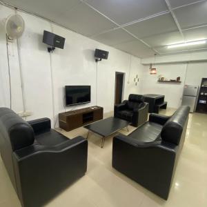 ein Wohnzimmer mit schwarzen Ledermöbeln und einem Flachbild-TV in der Unterkunft Beautiful River Homestay Kuala Pontian Rompin in Kuala Rompin