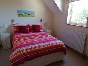 a bedroom with a large bed with a colorful blanket at Stunning Detached 3 Bedroom House Islandandmagee in Larne