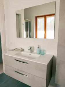 y baño con lavabo blanco y espejo. en La Betulla - appartamento indipendente con vista, en Ballabio