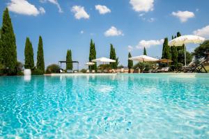 a large swimming pool with umbrellas and trees at Villa Asciano 20 by Mmega in Trequanda