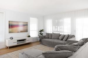 sala de estar blanca con sofá y TV en Amiri on Holbrook - Pet Friendly, en Yaroomba