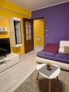 a living room with a purple bed and a tv at CORAL apartment in Târgu-Mureş