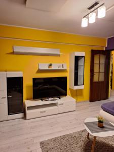 a living room with a large tv and a yellow wall at CORAL apartment in Târgu-Mureş