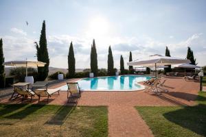 a large swimming pool with chairs and umbrellas at Villa Asciano 20 by Mmega in Trequanda