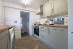 cocina con armarios blancos y fogones en StayRight 2 Bed House - Quick Drive to Brecon Beacons & more, en Griffithstown