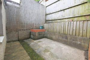 un patio trasero con una valla de madera y una olla en StayRight 2 Bed House - Quick Drive to Brecon Beacons & more, en Griffithstown
