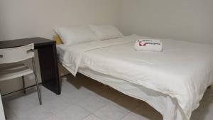 - une chambre avec un lit, un bureau et un couvre-lit blanc dans l'établissement Mjc New township 6BR by Natol Homestay-MJC, à Kuching