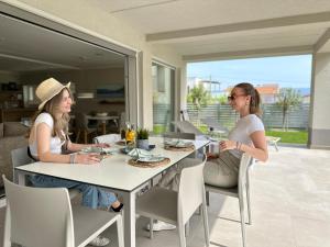 zwei Frauen an einem Tisch in einem Haus in der Unterkunft Apartment Baska - Main Building in Baška
