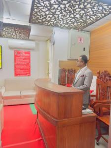 a man standing at a podium in a room at Hotel Rose Garden Palace Residential in Dhaka
