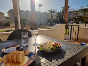 a table with two plates of food and a glass of wine at Poolside 2 Bedroom 2 Bathroom Apt, Ultra Fast Wi-Fi & Terrace in Los Alcázares