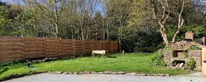 une clôture en bois dans une cour avec un panneau dans l'établissement Gîte du Chat noir (Brocéliande), à Campénéac