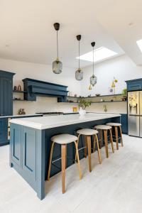 a kitchen with blue cabinets and bar stools at Beautiful large luxury home in London in Sidcup