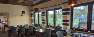 a dining room with tables and chairs and large windows at Hotel-Restaurant Hubertus in Brome