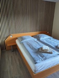 a bed with a wooden headboard with a towel on it at Hotel-Restaurant Hubertus in Brome