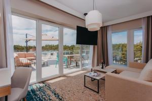 a living room with a couch and a television and a patio at Hotel Linea Mare in Pobierowo