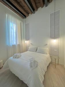 a white bedroom with a large white bed with towels on it at Dimora Manin in Verona