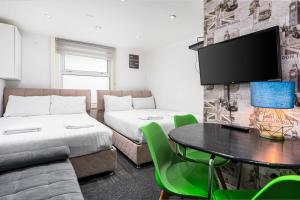 ロンドンにあるWhitechapel Grandのベッド2台、テーブル、テレビが備わる客室です。