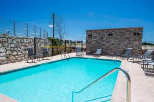 a swimming pool with chairs and a stone wall at Fairfield Inn & Suites by Marriott Dallas Waxahachie in Waxahachie