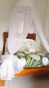 a bed with a canopy with white flowers on it at Meme Royak Homestay in Munduk