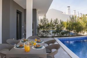 a table with food and drinks on a balcony with a pool at Villa Lagoa in Vau