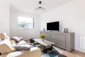 uma sala de estar com um sofá e uma televisão em Gîtes de la Mer - 4 Maisons avec piscine partagée em Erquy