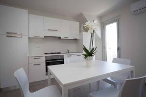 a white kitchen with a white table and white chairs at Palazzina Cala Luna Suite in San Benedetto del Tronto