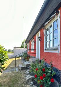 a red house with flowers in front of a window at Strandnära hus Abbekås in Abbekås +23 photos