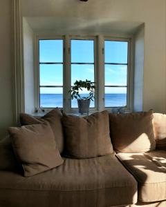 a brown couch in a living room with three windows at Strandnära hus Abbekås in Abbekås