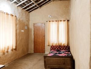 une chambre vide avec un lit et une porte en bois dans l'établissement Cosmic Mud House Kanthalloor, à Kanthalloor