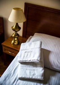 a pair of towels sitting on a bed with a lamp at Aparthotel Basztowa in Krakow