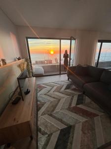 een woonkamer met een bank en uitzicht op de oceaan bij CUSTÓDIO SEA HOME in Praia de Mira