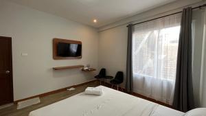 Schlafzimmer mit einem Bett, einem TV und einem Fenster in der Unterkunft RedDoorz Premium at Jalan Diponegoro Lampung in Bandar Lampung
