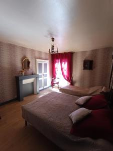 1 dormitorio con 2 camas, cortinas rojas y chimenea en Descartes en Descartes