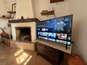 a large flat screen tv in a living room with a fireplace at Casa Rural “Los Campos” in Almogía