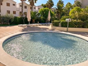 a large swimming pool in a courtyard with umbrellas at Bga rentals Punta Prima in La Pineda