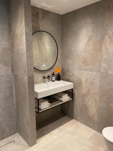 een badkamer met een wastafel en een spiegel bij Boutique Hotel Herbergh Amsterdam Airport FREE PARKING in Badhoevedorp