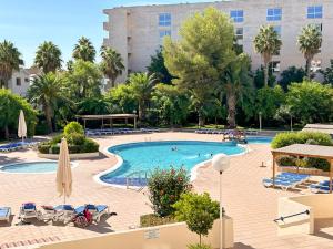 a pool with chairs and umbrellas and a building at Bga rentals Punta Prima in La Pineda
