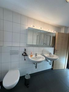 een badkamer met 2 wastafels en een toilet bij Ferienwohnung Bodenseeblick in Hagnau