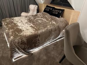 a bed with a silver comforter and a chair at Skyline Villa with jacuzzi and sauna in Kościelisko