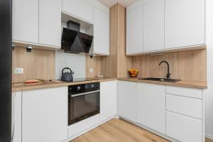 a kitchen with white cabinets and a sink at Cosy Apartment with Terrace and Parking in Rumia by Rent like home in Rumia
